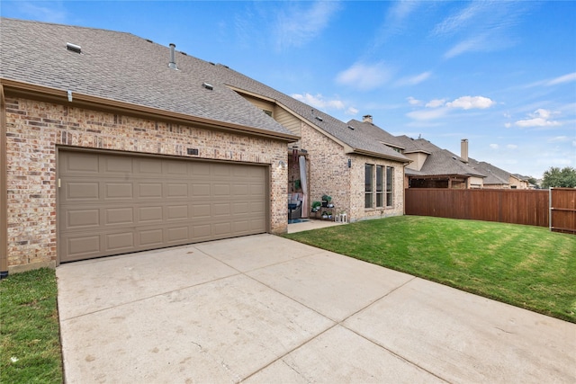 view of front of property featuring a front lawn, fence, roof with shingles, concrete driveway, and brick siding