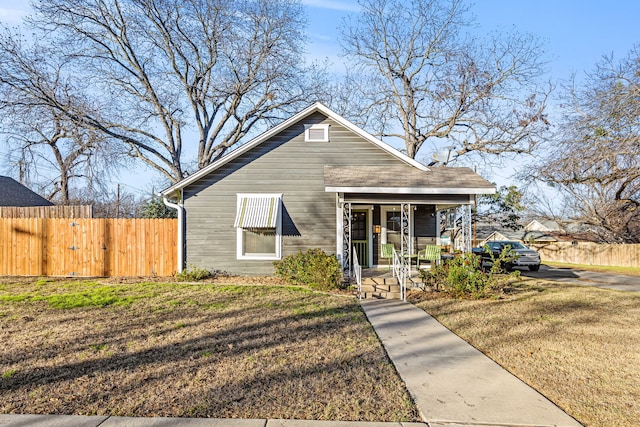 bungalow-style house featuring a porch, a front lawn, and fence