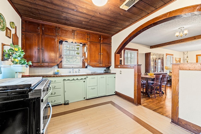 kitchen with light wood finished floors, visible vents, green cabinets, arched walkways, and stainless steel gas range