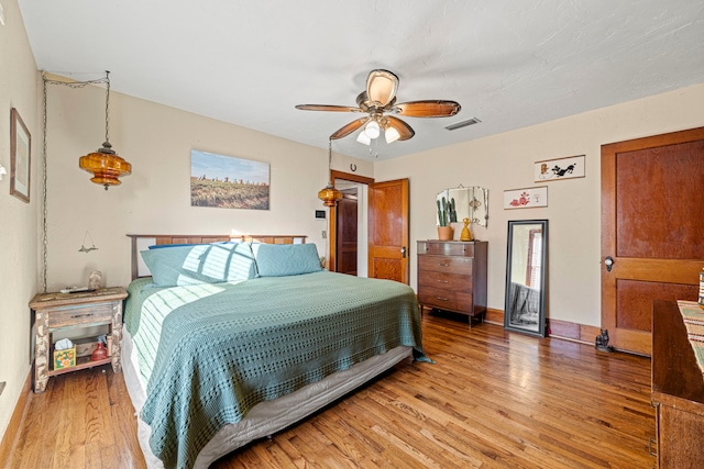 bedroom with light wood finished floors, visible vents, baseboards, and ceiling fan