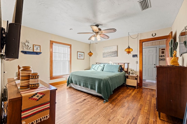 bedroom with visible vents, baseboards, wood finished floors, and a ceiling fan