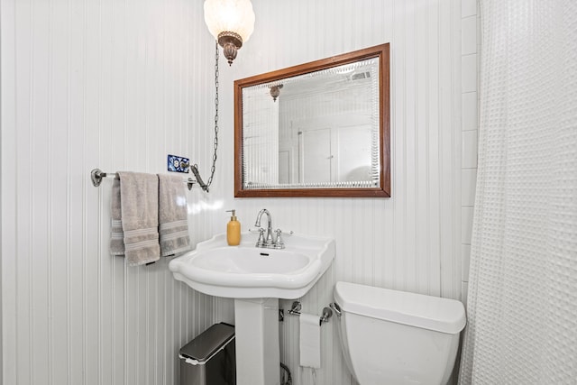 full bath featuring curtained shower, toilet, and a sink