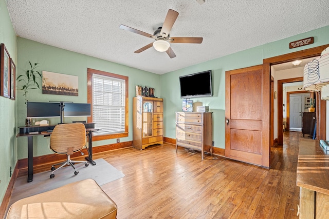 office featuring ceiling fan, wood finished floors, baseboards, and a textured ceiling