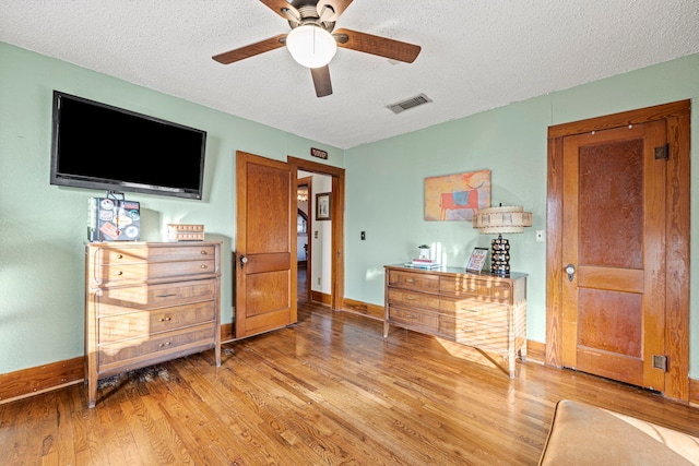 bedroom with baseboards, wood finished floors, visible vents, and a textured ceiling