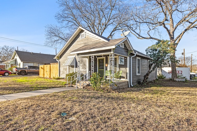 bungalow-style house with covered porch, a front yard, and fence