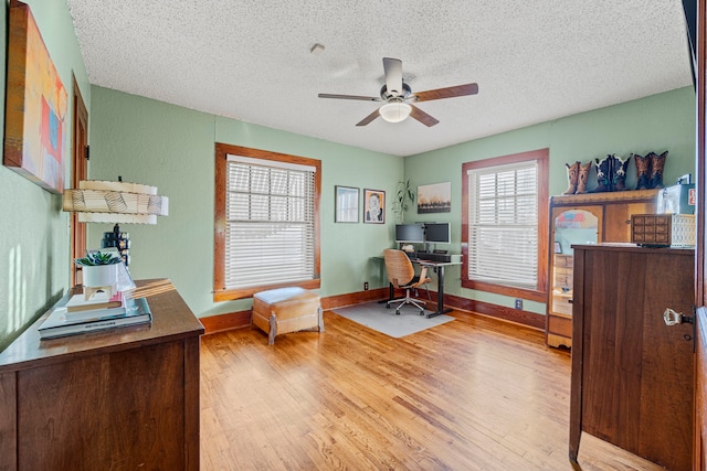 home office with baseboards, a textured ceiling, wood finished floors, and a ceiling fan