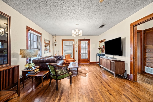 living area featuring a chandelier, visible vents, and hardwood / wood-style floors