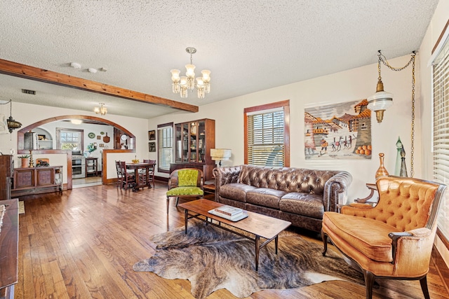 living room featuring visible vents, an inviting chandelier, arched walkways, a textured ceiling, and wood-type flooring