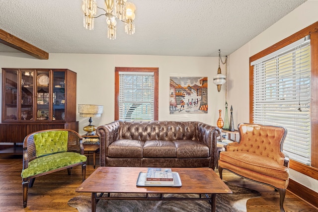 living room featuring beamed ceiling, a textured ceiling, an inviting chandelier, and wood finished floors