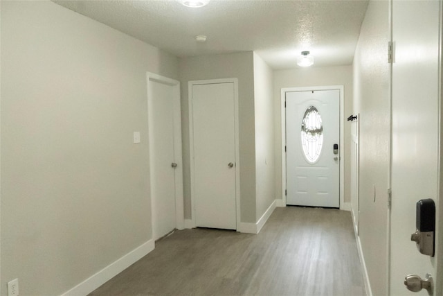 entryway with light wood-type flooring, baseboards, and a textured ceiling