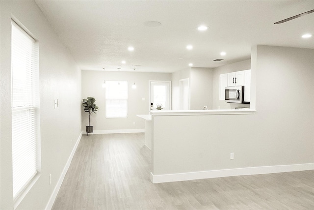 kitchen with stainless steel microwave, recessed lighting, light wood-type flooring, and baseboards