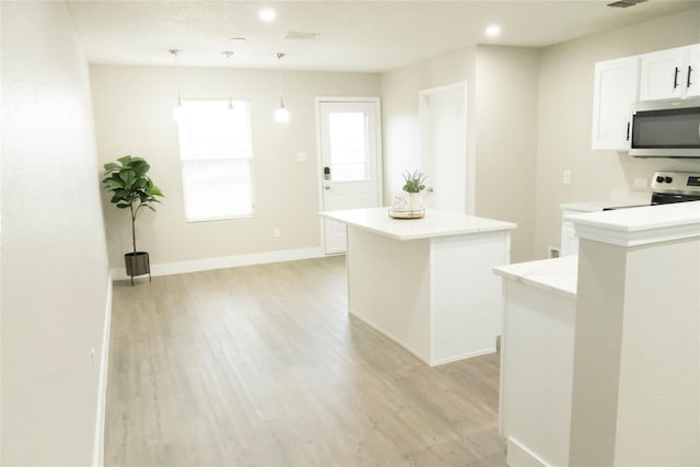 kitchen with a center island, light wood-style floors, appliances with stainless steel finishes, light countertops, and baseboards