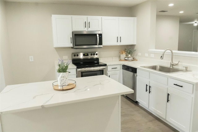 kitchen with light wood finished floors, visible vents, stainless steel appliances, white cabinetry, and a sink