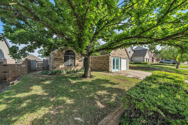 view of yard with fence, french doors, and a garage