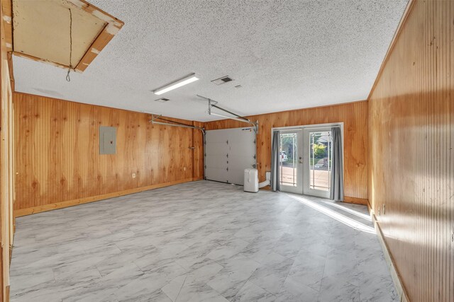 interior space featuring wooden walls, french doors, attic access, and electric panel