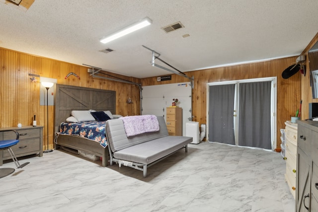 bedroom featuring visible vents, wooden walls, marble finish floor, and a textured ceiling