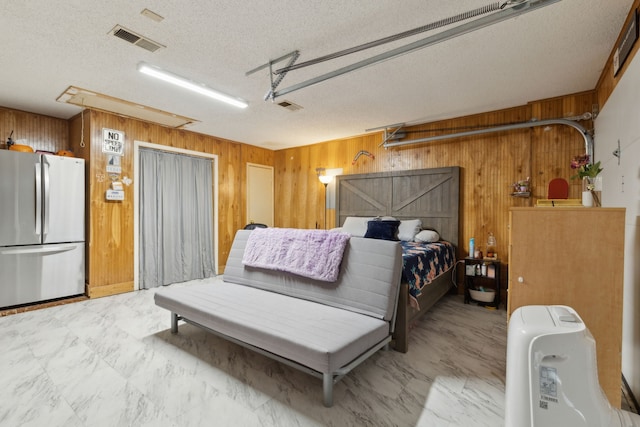 bedroom featuring visible vents, marble finish floor, freestanding refrigerator, wooden walls, and a garage