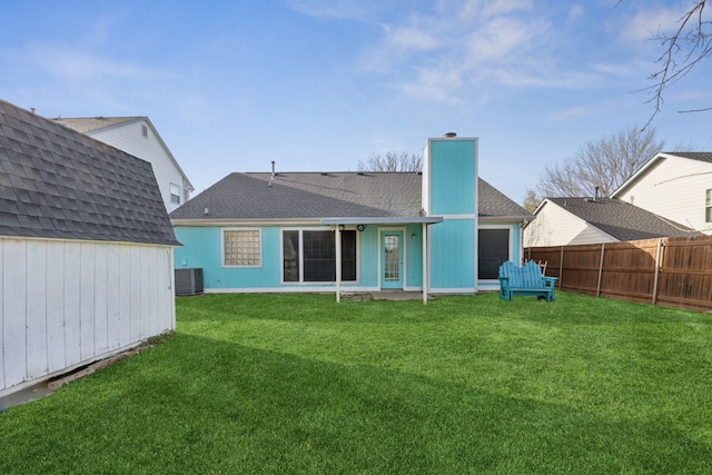 rear view of property featuring fence, central AC unit, a chimney, an outdoor structure, and a yard