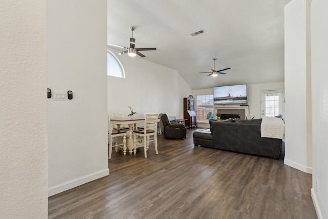 living room with visible vents, dark wood-type flooring, a fireplace, lofted ceiling, and ceiling fan