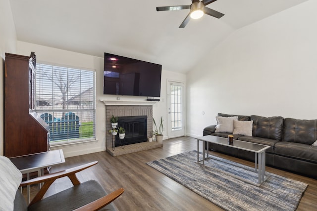 living area featuring a brick fireplace, ceiling fan, baseboards, lofted ceiling, and wood finished floors