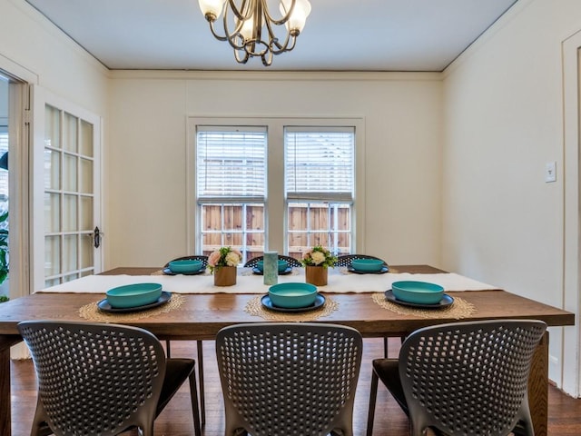 dining space featuring wood finished floors, a chandelier, and crown molding