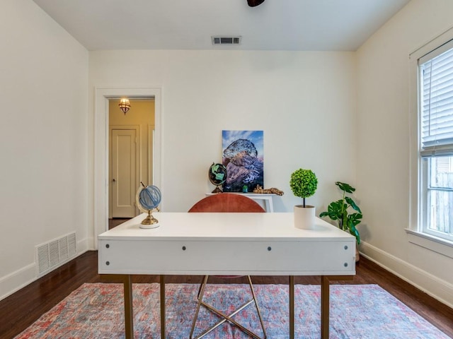 office area with plenty of natural light, dark wood-style floors, visible vents, and baseboards