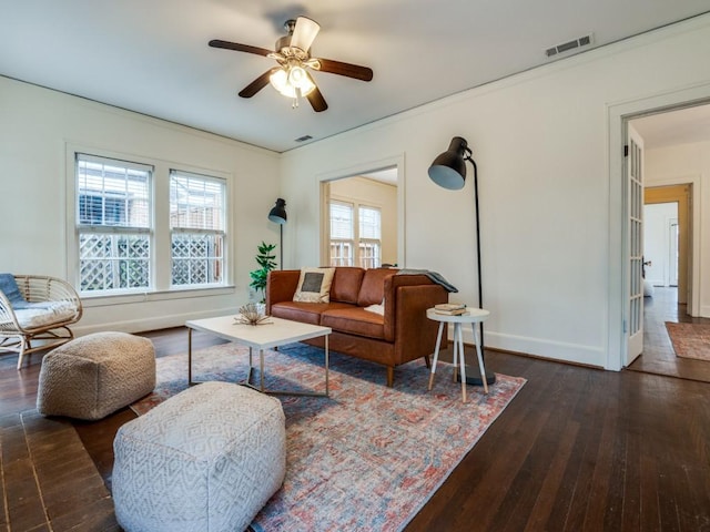 living room featuring visible vents, a ceiling fan, baseboards, and dark wood-style flooring