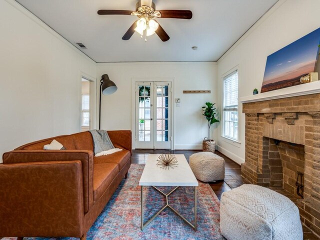 living area with visible vents, baseboards, french doors, a fireplace, and wood finished floors