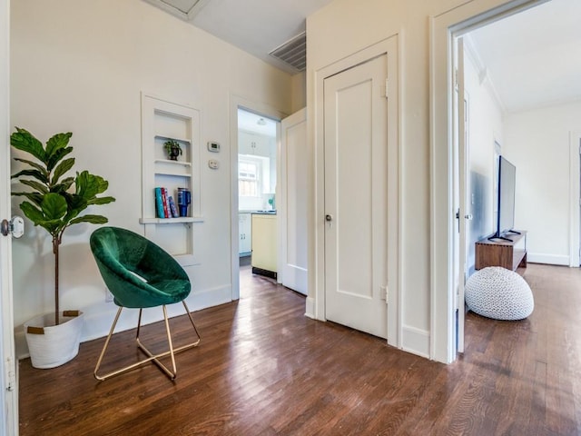 hallway featuring built in features, wood finished floors, visible vents, and baseboards