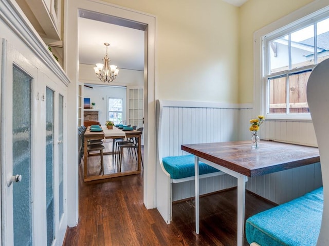 dining space featuring a wealth of natural light, a notable chandelier, wainscoting, and wood finished floors