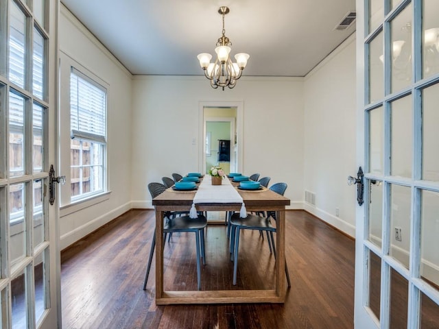 dining area with dark wood finished floors, visible vents, and a chandelier