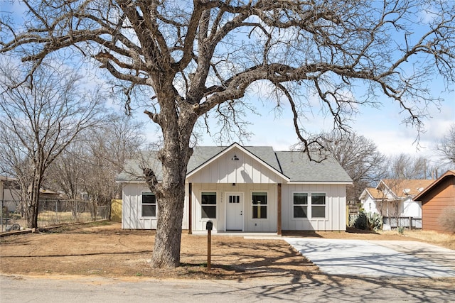 modern farmhouse style home with a porch, fence, board and batten siding, and roof with shingles