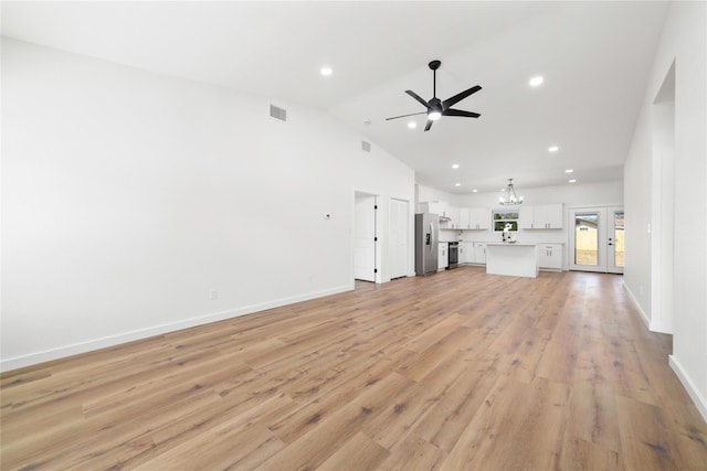 unfurnished living room with recessed lighting, light wood-style flooring, ceiling fan with notable chandelier, and baseboards