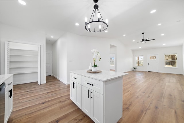 kitchen featuring light wood finished floors, dishwashing machine, white cabinetry, and hanging light fixtures