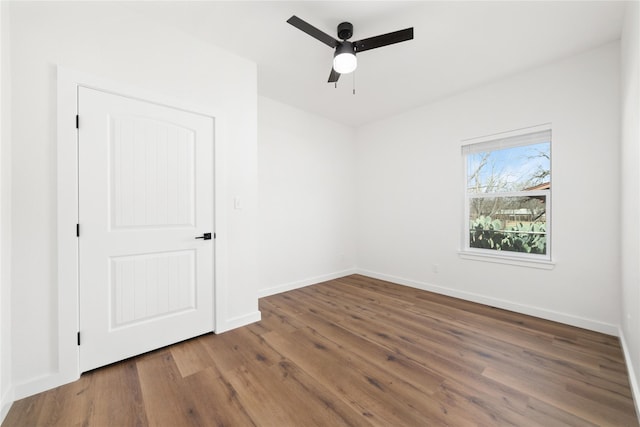 empty room with a ceiling fan, wood finished floors, and baseboards