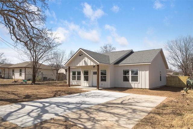 modern farmhouse style home featuring board and batten siding, a shingled roof, and fence