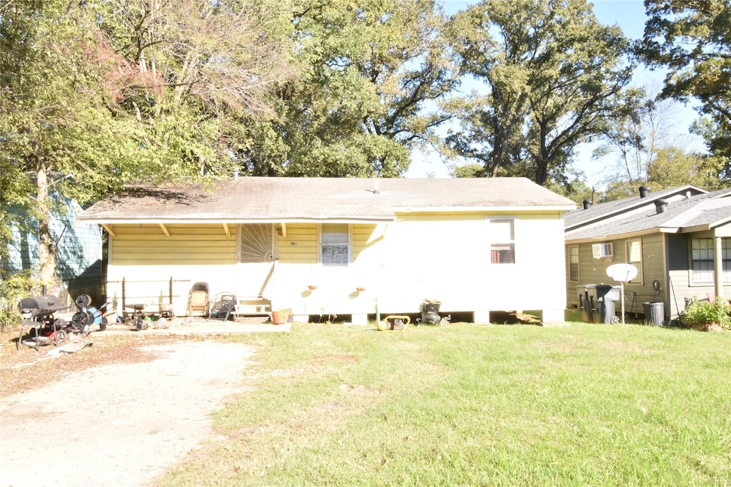 back of property featuring a lawn and driveway