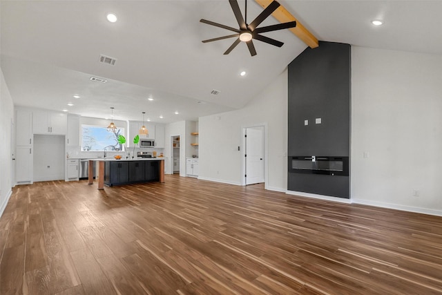 unfurnished living room with visible vents, baseboards, ceiling fan, beamed ceiling, and wood finished floors