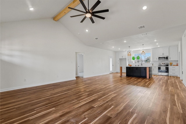 unfurnished living room featuring visible vents, baseboards, beamed ceiling, wood finished floors, and a sink