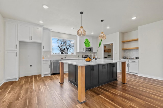 kitchen with light wood-type flooring, light countertops, appliances with stainless steel finishes, white cabinets, and open shelves