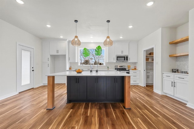 kitchen featuring appliances with stainless steel finishes, white cabinetry, light countertops, and open shelves