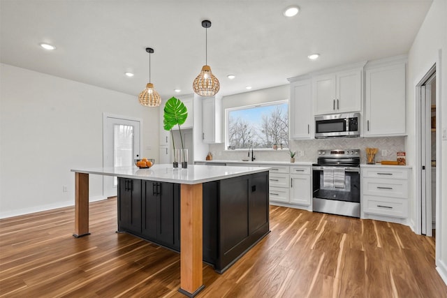 kitchen featuring wood finished floors, a sink, stainless steel appliances, light countertops, and white cabinetry