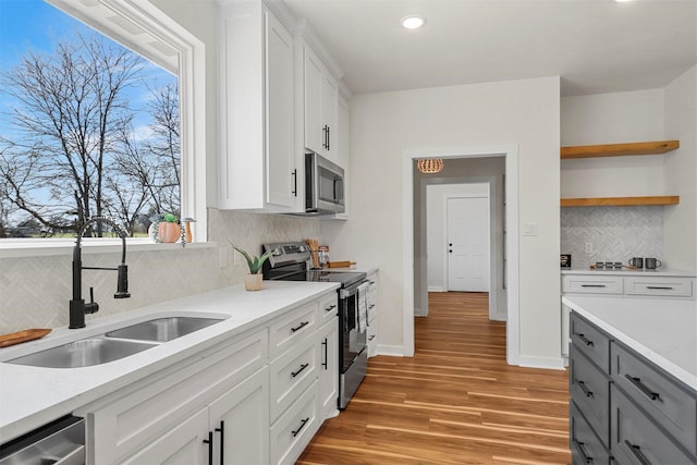 kitchen with baseboards, light countertops, appliances with stainless steel finishes, light wood-style floors, and a sink