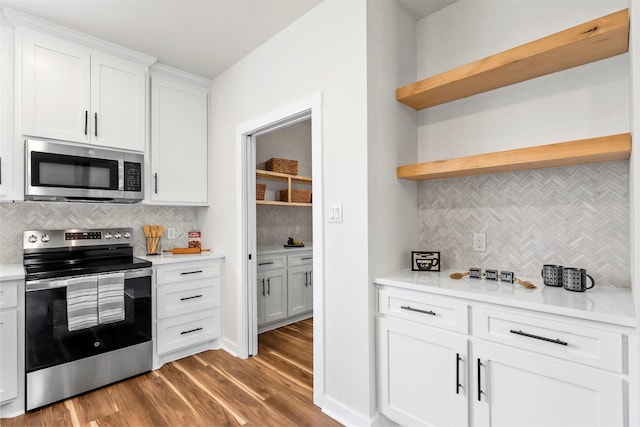 kitchen with wood finished floors, open shelves, light countertops, white cabinets, and appliances with stainless steel finishes