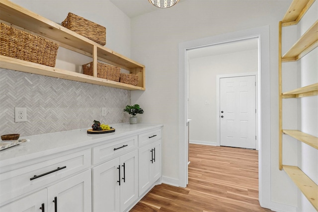 bar with light wood-style floors, baseboards, and tasteful backsplash