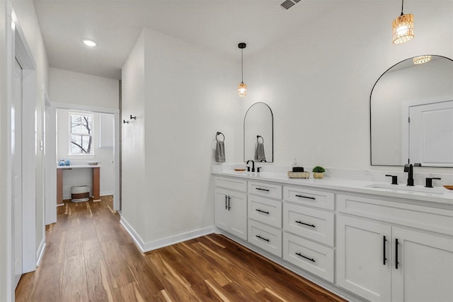 bathroom with a sink, baseboards, wood finished floors, and double vanity