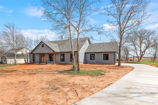 modern inspired farmhouse with board and batten siding, roof with shingles, and a chimney