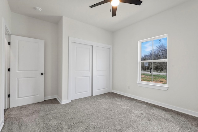 unfurnished bedroom with baseboards, carpet floors, a closet, and a ceiling fan