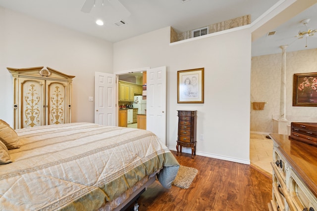 bedroom featuring visible vents, ceiling fan, baseboards, freestanding refrigerator, and wood finished floors