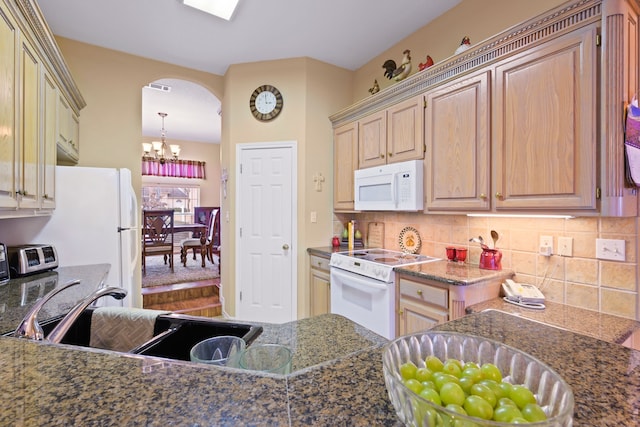 kitchen featuring white appliances, an inviting chandelier, arched walkways, a sink, and tasteful backsplash